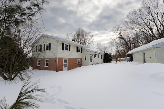 view of snowy exterior with brick siding