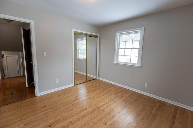 unfurnished bedroom with light wood-type flooring, a closet, and baseboards