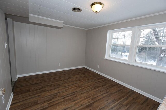 unfurnished room featuring dark wood-style floors, baseboards, visible vents, and crown molding