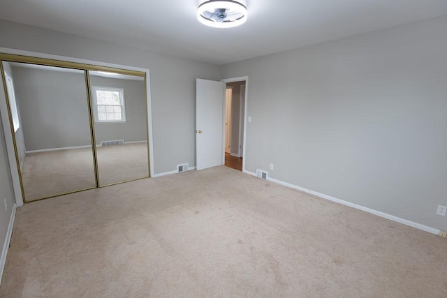 unfurnished bedroom with light colored carpet, visible vents, and baseboards