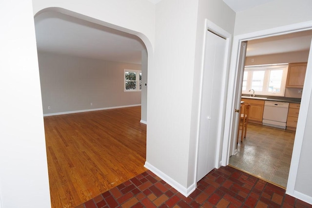 hall with arched walkways, baseboards, and a healthy amount of sunlight