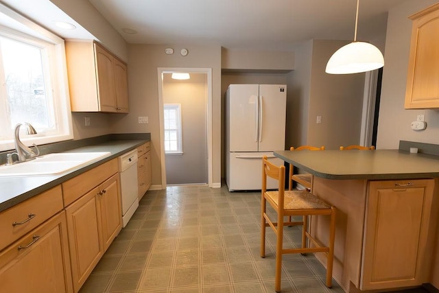 kitchen with white appliances, dark countertops, a breakfast bar, pendant lighting, and a sink