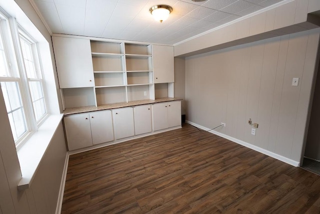 interior space featuring dark wood-style floors, ornamental molding, and baseboards