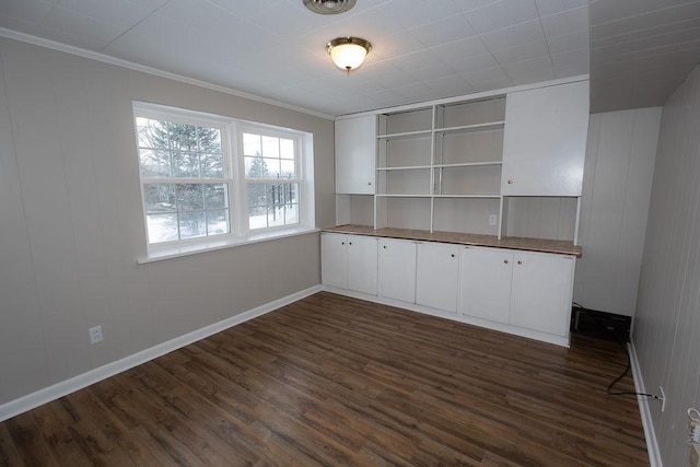 interior space with dark wood-style flooring, crown molding, and baseboards