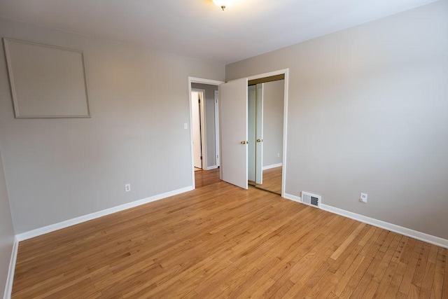 spare room featuring light wood finished floors, visible vents, and baseboards