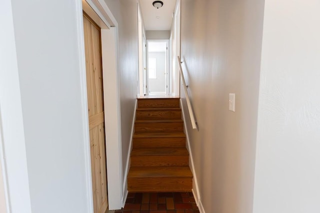 stairs featuring brick floor and baseboards