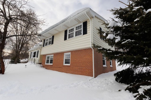 view of snow covered exterior featuring brick siding