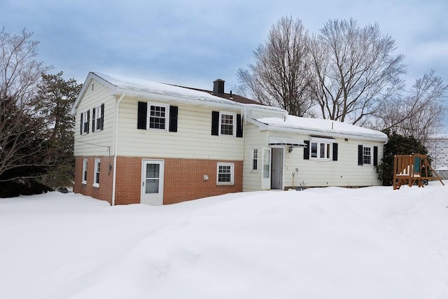 split level home featuring a chimney and brick siding