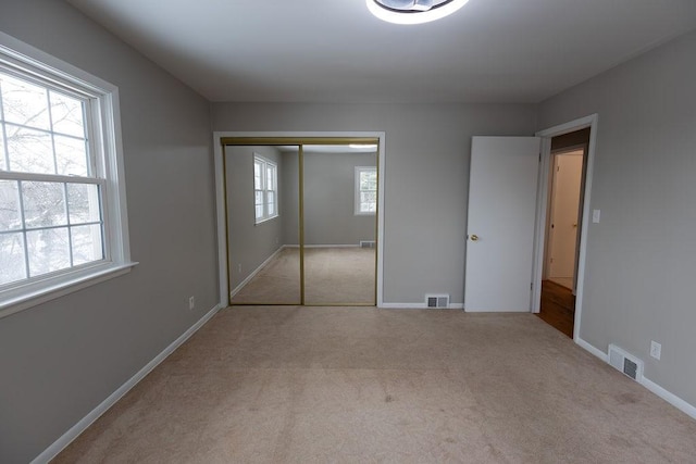 unfurnished bedroom with light carpet, multiple windows, and visible vents