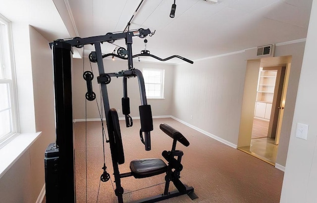 workout area featuring baseboards, visible vents, and crown molding