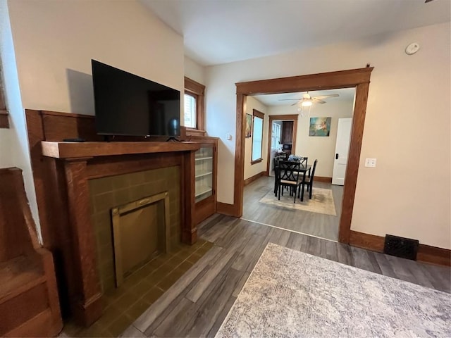 living room with baseboards, a fireplace with flush hearth, ceiling fan, and dark wood-style flooring