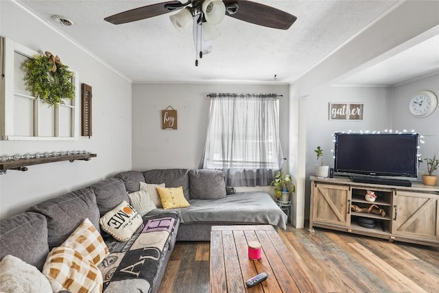 living room featuring ceiling fan, hardwood / wood-style flooring, ornamental molding, and a textured ceiling