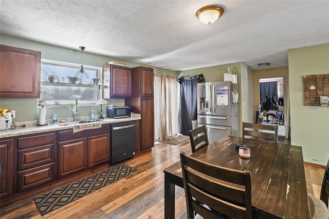 kitchen featuring pendant lighting, sink, dark wood-type flooring, stainless steel appliances, and a textured ceiling