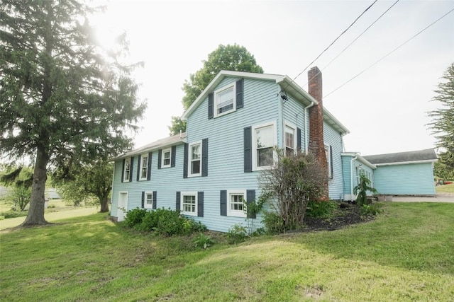 view of side of home with a yard and a chimney