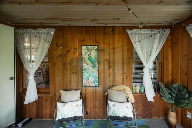 sitting room featuring wood walls and carpet