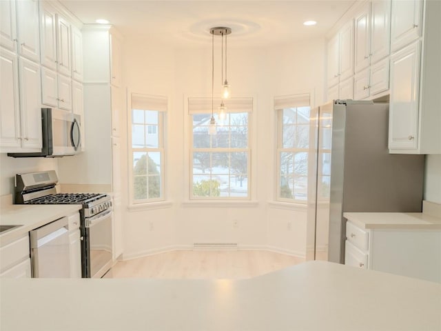 kitchen with stainless steel appliances, white cabinetry, and hanging light fixtures