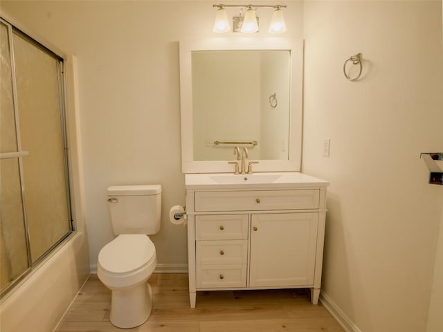 full bathroom featuring vanity, wood-type flooring, toilet, and bath / shower combo with glass door