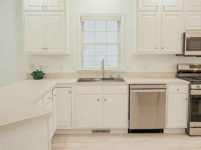 kitchen featuring white cabinetry, appliances with stainless steel finishes, sink, and light wood-type flooring