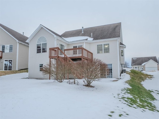 snow covered back of property with a wooden deck