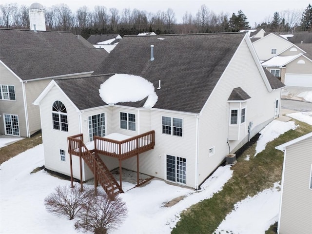 snow covered house featuring central AC and a deck