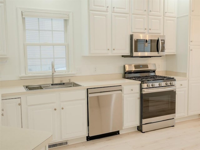 kitchen with stainless steel appliances, white cabinetry, and sink