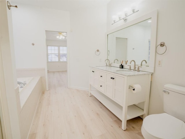 bathroom featuring hardwood / wood-style floors, vanity, ceiling fan, toilet, and a bath