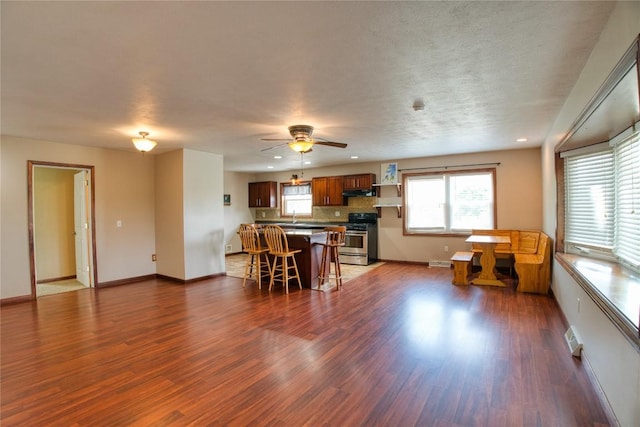 13151 Water Ext, Edinboro, PA 16412 - kitchen featuring stainless steel stove, a kitchen bar, under cabinet range hood, dark wood finished floors, and ceiling fan