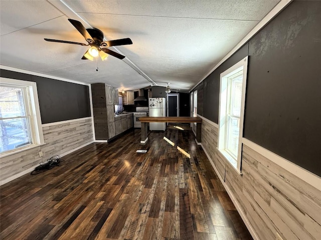 interior space featuring dark hardwood / wood-style flooring, crown molding, vaulted ceiling, and wood walls