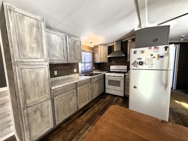 kitchen featuring sink, vaulted ceiling, dark hardwood / wood-style floors, white appliances, and wall chimney range hood