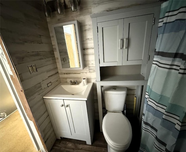 bathroom with vanity, toilet, and wood walls