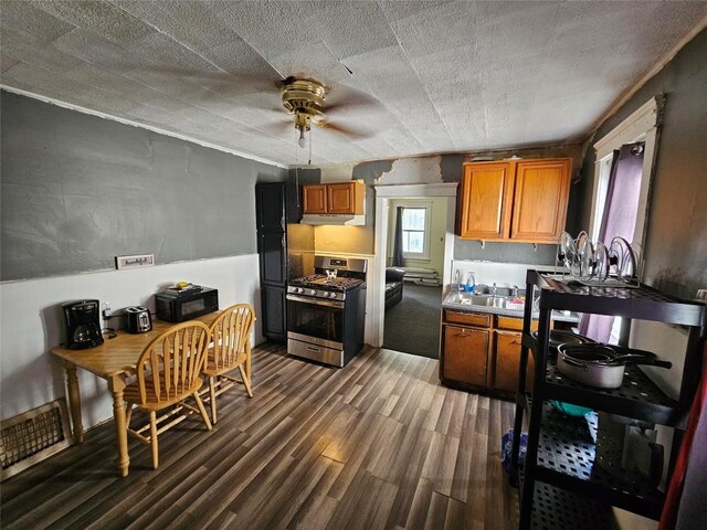520 E 2nd St, Erie, PA 16507 - kitchen featuring gas stove, ceiling fan, under cabinet range hood, dark wood-type flooring, and brown cabinetry