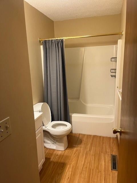 full bathroom featuring shower / bath combo with shower curtain, vanity, a textured ceiling, and toilet