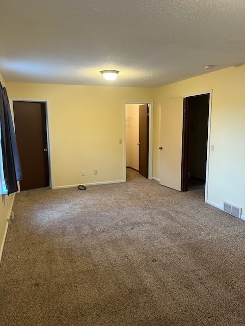 carpeted empty room featuring a textured ceiling