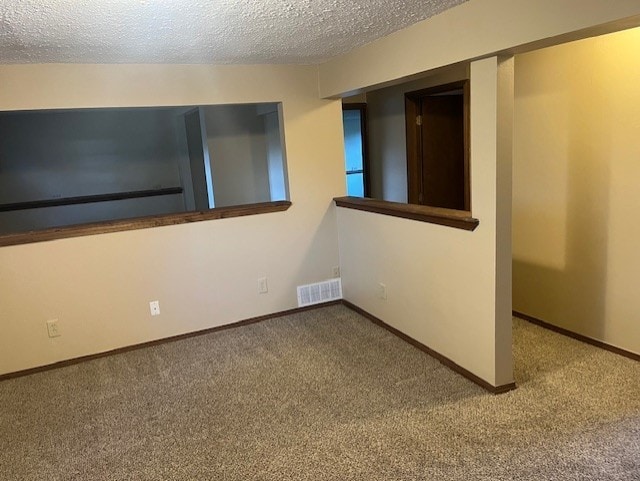 carpeted spare room featuring a textured ceiling