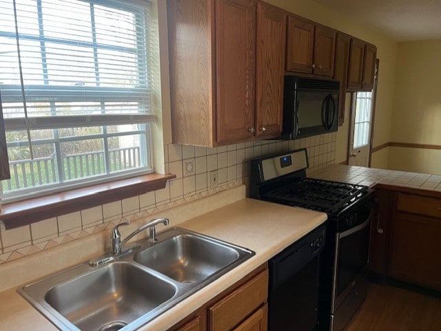 kitchen with decorative backsplash, sink, and black appliances