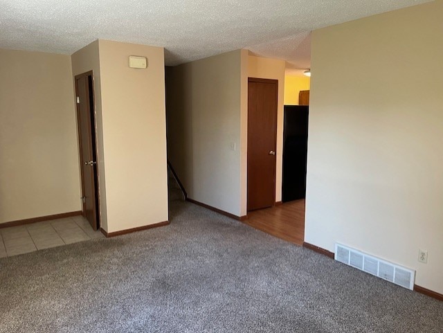 carpeted empty room featuring a textured ceiling