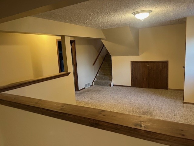 bonus room featuring a textured ceiling and dark colored carpet