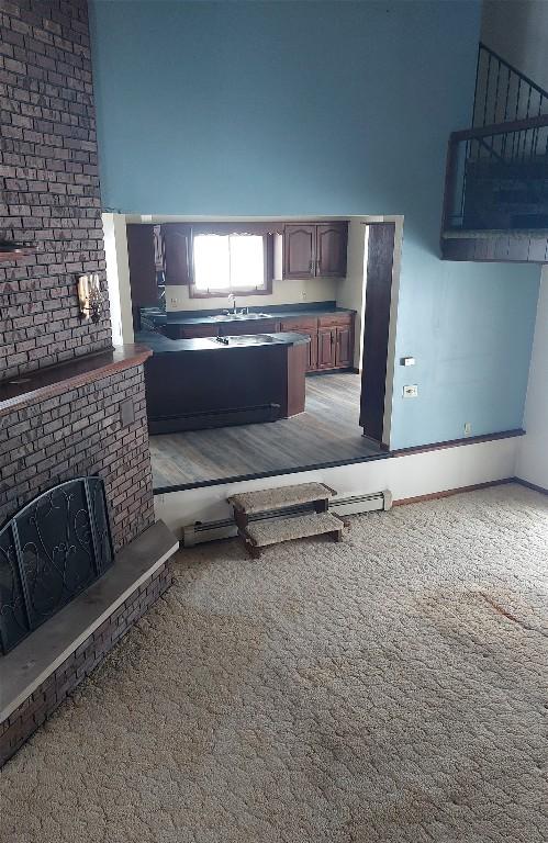 kitchen featuring a peninsula, carpet flooring, a sink, a towering ceiling, and dark countertops