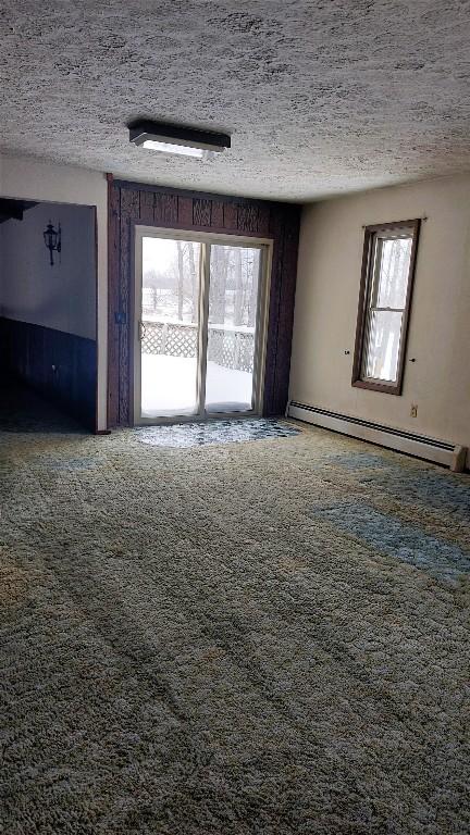 interior space with a textured ceiling, carpet floors, and baseboard heating