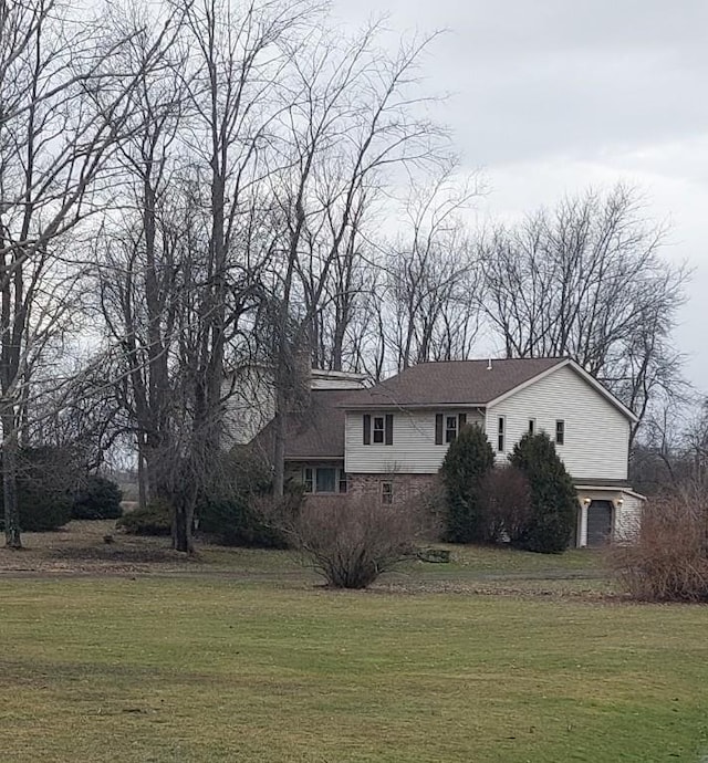 view of side of property with dirt driveway, a lawn, and a garage