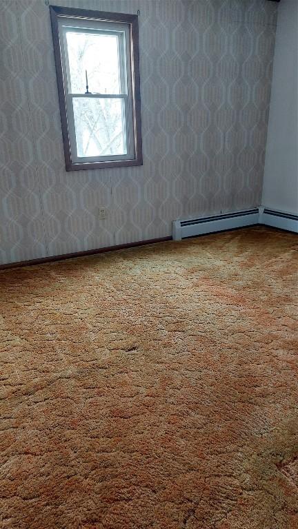 carpeted empty room with baseboard heating