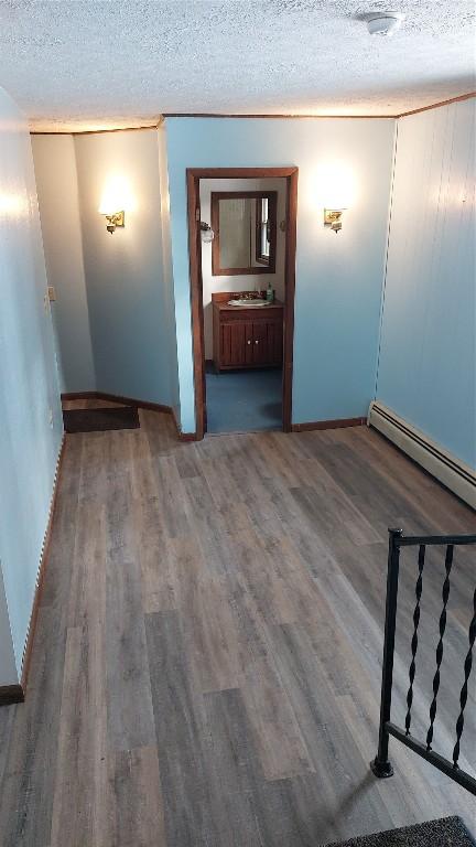 spare room featuring baseboard heating, a textured ceiling, and hardwood / wood-style flooring