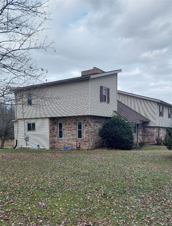 view of property exterior with brick siding and a yard