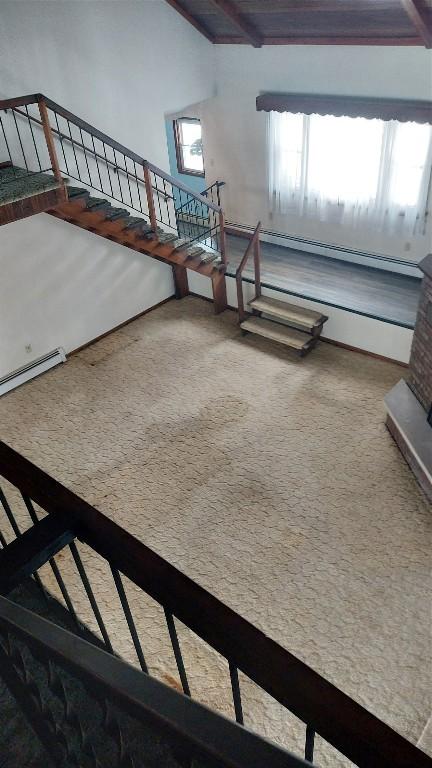 staircase with carpet, beam ceiling, and a baseboard heating unit