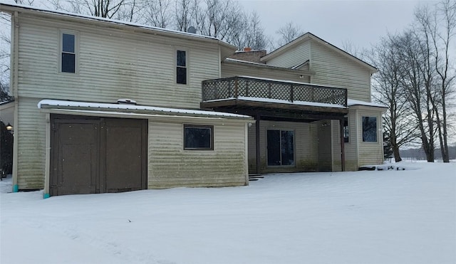 snow covered rear of property featuring a balcony