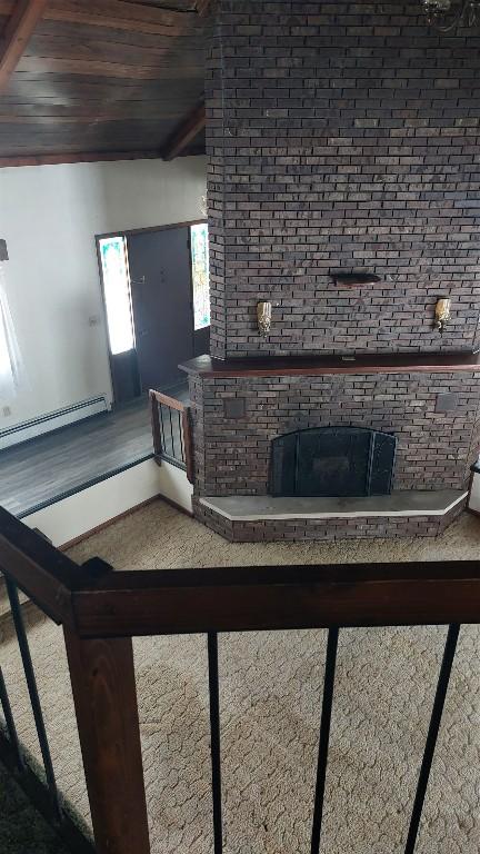 living room featuring a baseboard radiator, a brick fireplace, and wood ceiling