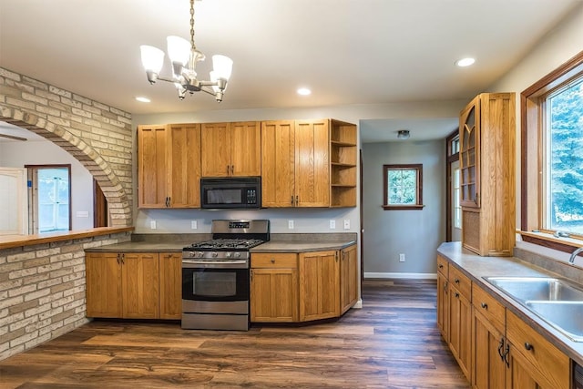 kitchen with sink, stainless steel gas stove, decorative light fixtures, brick wall, and a chandelier