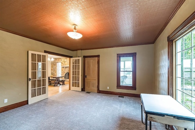 interior space featuring french doors, carpet floors, a healthy amount of sunlight, and ornamental molding