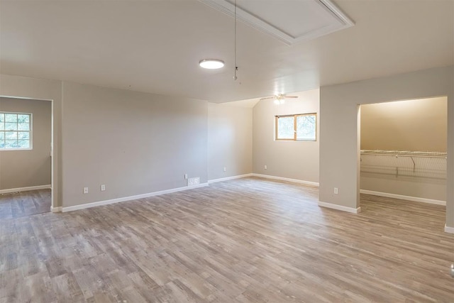 empty room with ceiling fan, a healthy amount of sunlight, and light wood-type flooring