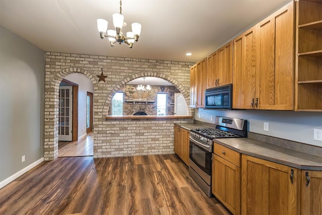 kitchen featuring dark hardwood / wood-style flooring, brick wall, stainless steel gas range, decorative light fixtures, and a notable chandelier